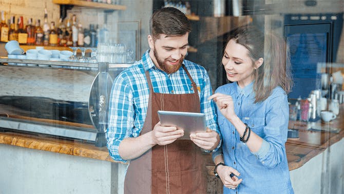 Registrierkasse für die Gastronomie Kellner und Kundin schauen auf ein Tablet Kassensystem