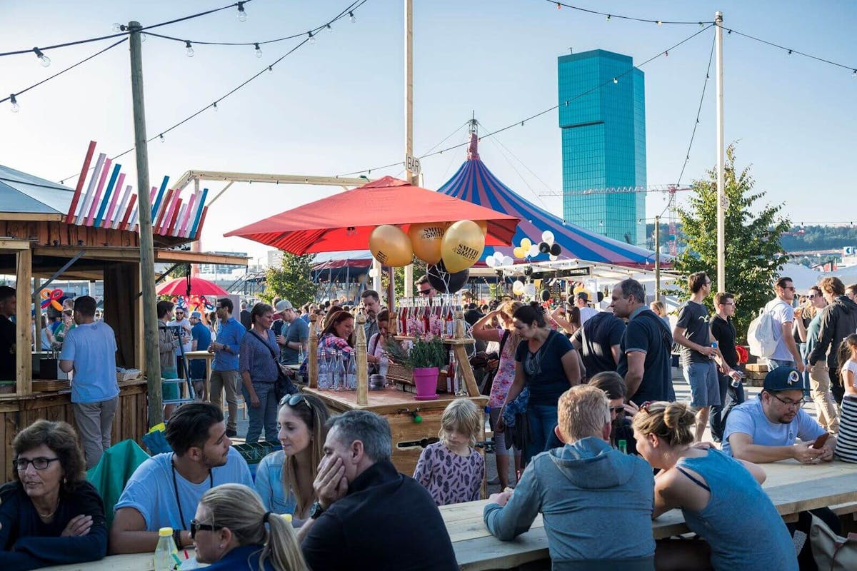 street food Menschen auf einem street food festival, verschiedene Zelte, im Hintergrund ein Hochhaus