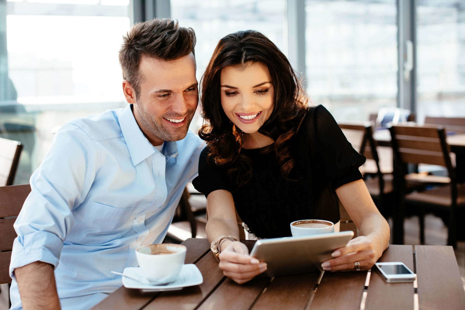 zwei Personen sehen auf Tablet in einem Café