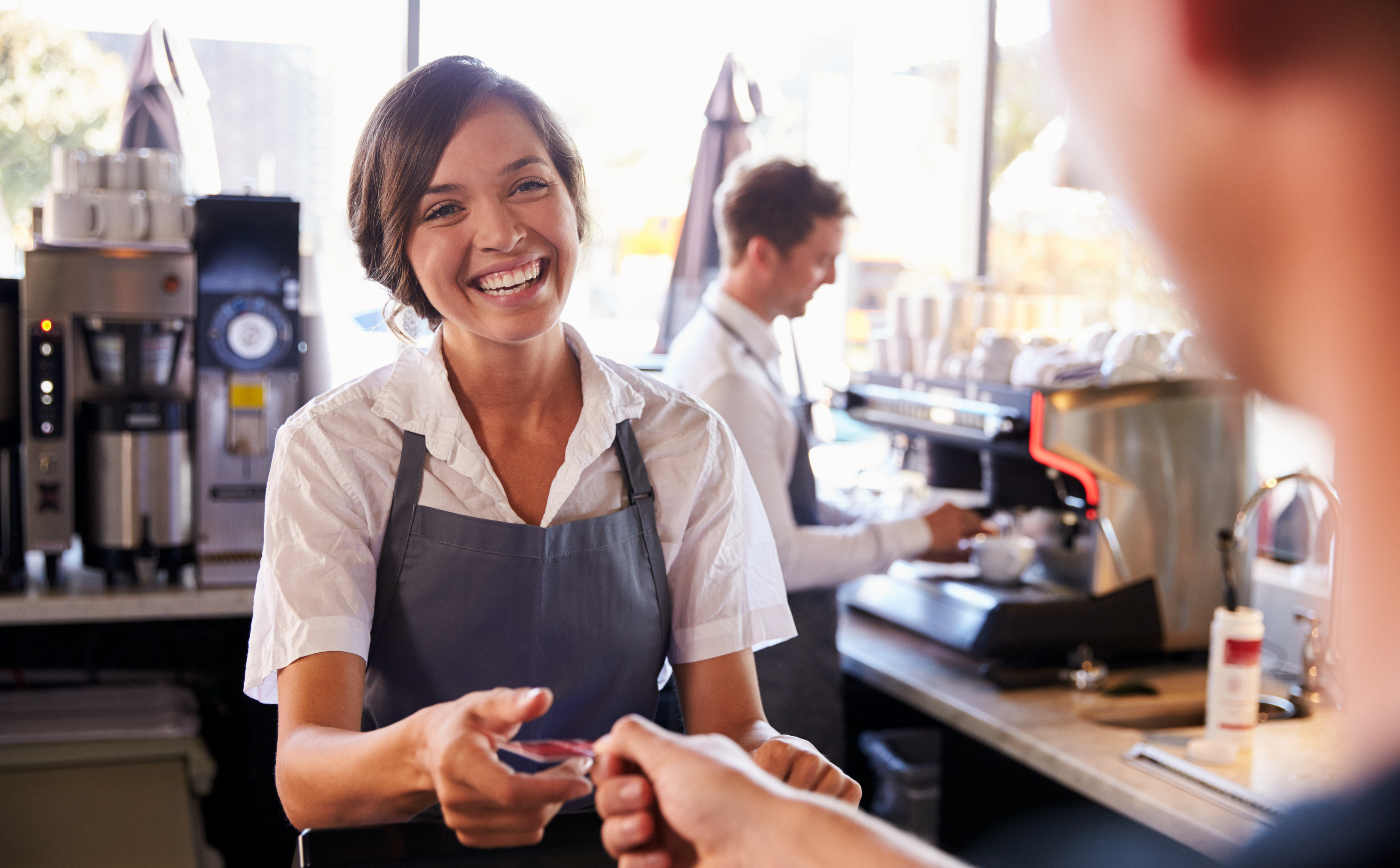 Kartenzahlung mit ready2order: Frau nimmt Karte am Tresen entgegen