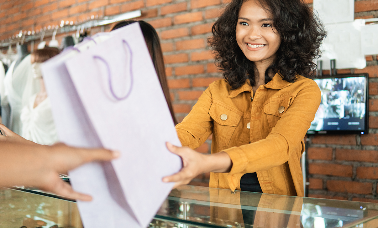 Verkäuferin übergibt Einkaufstüte