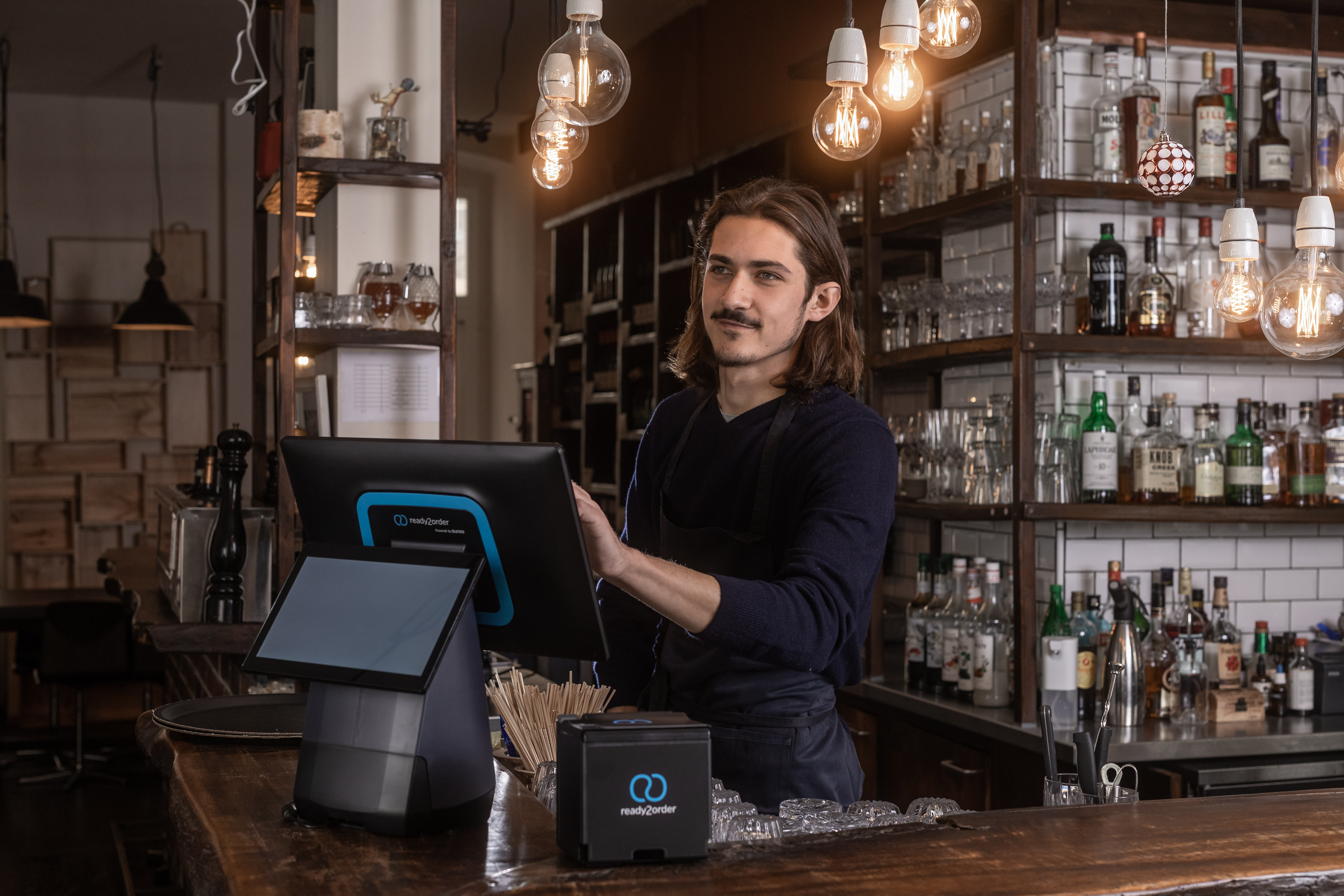 Junger Mann bedient Kassengerät readyMax in einer Bar.