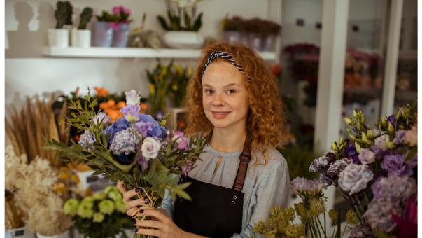 Frau in einem Blumenladen mit Blumenstrauß in der Hand