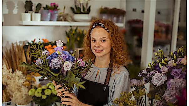 Kassensystem für Handel - Blumenladen Frau in einem Blumenladen mit Blumenstrauß in der Hand