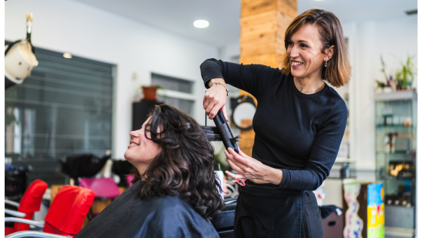 Friseurin wellt einer Kundin das Haar mit dem