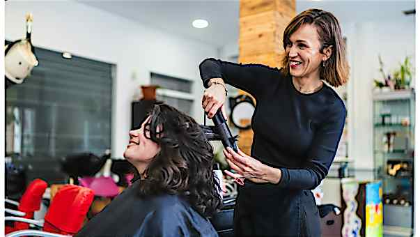 Kassensystem Dienstleistungen - Friseure Friseurin wellt einer Kundin das Haar mit dem